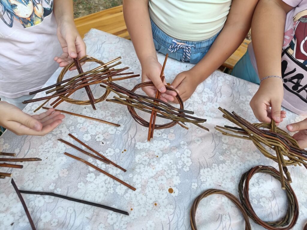 Hands shaping willow at a workshop table