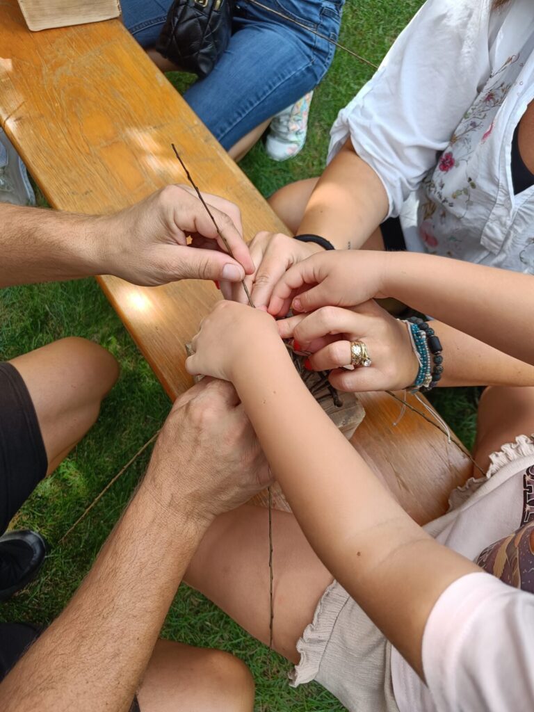 Small and grown-up hands weaving willow together